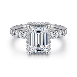 Gabriel & Co. ER16568E10W44JJ 14 karat white gold Contemporary engagement ring, front view of an emerald cut center in corner claws with diamonds peeking around its edge