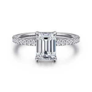 Gabriel & Co. ER16570E6W44JJ 14 karat white gold Contemporary engagement ring, front view of an emerald cut center between four corner prongs and small round diamonds on the band