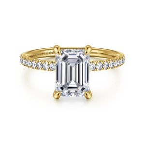 Gabriel & Co. ER16570E8Y44JJ 14 karat yellow gold Contemporary engagement ring, front view of an emerald cut center held by four prongs above small stones on the shoulders
