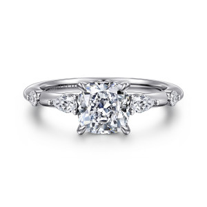 Gabriel & Co. ER16666C6W44JJ 14 karat white gold Starlight engagement ring, front view of a cushion cut center in four prongs between elongated diamonds on the shoulders