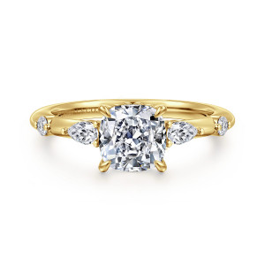 Gabriel & Co. ER16666C6Y44JJ 14 karat yellow gold Starlight engagement ring, front view of a cushion cut center flanked by elongated and round diamonds set apart on the band