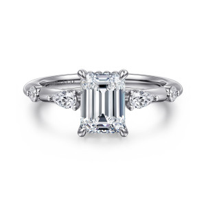Gabriel & Co. ER16666E6W44JJ 14 karat white gold Starlight engagement ring, front view of an emerald cut center flanked by elongated and round diamonds set apart along the shoulders