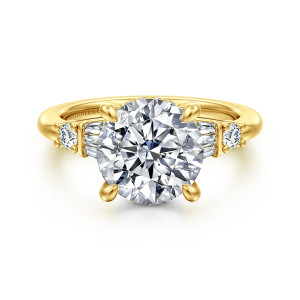 Gabriel & Co. ER16676R12Y44JJ 14 karat yellow gold Contemporary engagement ring, front view of a round center on four prongs with baguettes and a round diamond on each shoulder