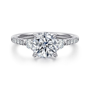 Gabriel & Co. ER16769R6W44JJ 14 karat white gold Lotus engagement ring, front view of a round center held by four prongs with a larger diamond tucked on each side