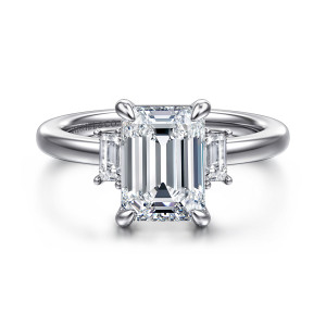 Gabriel & Co. ER16785E10W43JJ 14 karat white gold Contemporary engagement ring, front view of an emerald cut center between step cut side stones on a plain band
