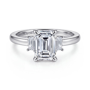 Gabriel & Co. ER16785E8W43JJ 14 karat white gold Contemporary engagement ring, front view of an emerald cut center between two step cut side stones on a polished band