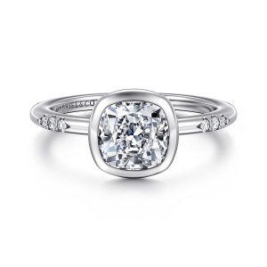 Gabriel & Co. ER16857C6W44JJ 14 karat white gold Contemporary engagement ring, front view of the smooth bezel around a cushion cut center with diamond clusters at the shoulders