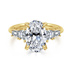 Gabriel & Co. ER16912O12Y43JJ 14 karat yellow gold Classic engagement ring, front view of an oval center with teardrop tipped claws between tapered baguette stones