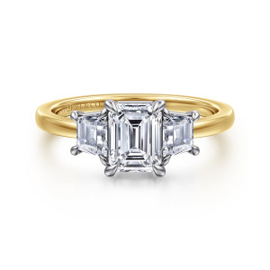 Gabriel & Co. ER17090E4M43JJ 14 karat white and yellow gold Contemporary engagement ring, front view of an emerald cut between trapezoid side stones on a lighter head