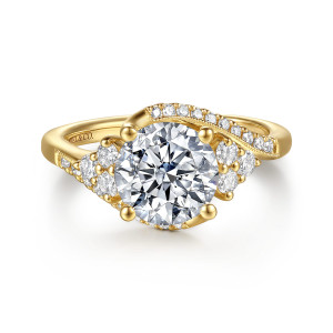 Gabriel & Co. ER17385R8Y44JJ 14 karat yellow gold Victorian engagement ring, front view of a round center in ball tipped prongs beside a bypass ribbon of small diamonds
