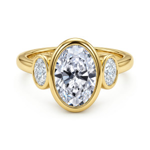 Gabriel & Co. ER17400O8Y44JJ 14 karat yellow gold Contemporary engagement ring, front view of an oval center in a smooth bezel flanked by smaller bezel set stones
