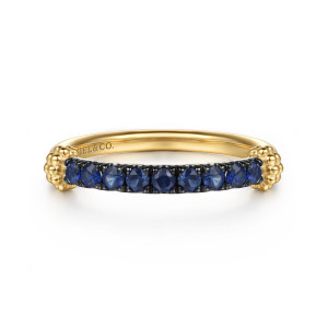 Gabriel & Co. LR52922Y4JSA 14 karat yellow gold Bujukan ring, front view of the bar of deep blue stones on a darkened bed between two bead clusters