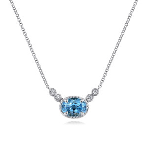 Gabriel & Co. NK5937W45BT 14 karat white gold Hampton necklace, front view of the sideways oval blue stone, its twisted frame and the bezel set diamonds beside it