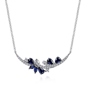 Gabriel & Co. NK6348W45SA 14 karat white gold Color necklace, front view of the crescent bar, its crossing pave band and blue pear stones