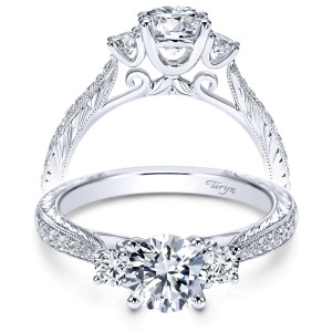 Taryn TE7287W44JJ 14 karat white gold engagement ring, front view of a round center between two side stones on engraved milgrain shoulders with scroll gallery
