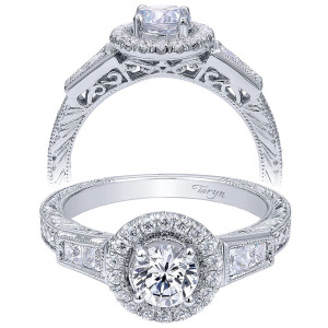 Taryn TE99064W44JJ 14 karat white gold engagement ring, front view of a round center in a halo above square cut shoulder stones with engraved sides