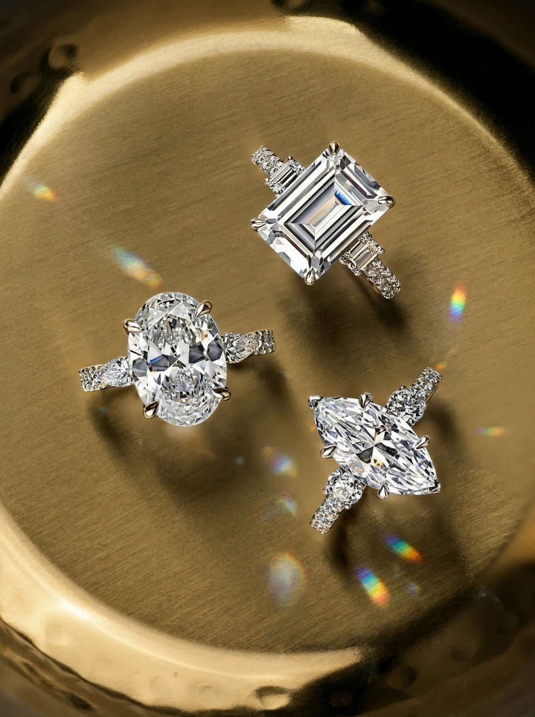 Oval, emerald-cut and marquise A.JAFFE diamond engagement rings on a golden tray