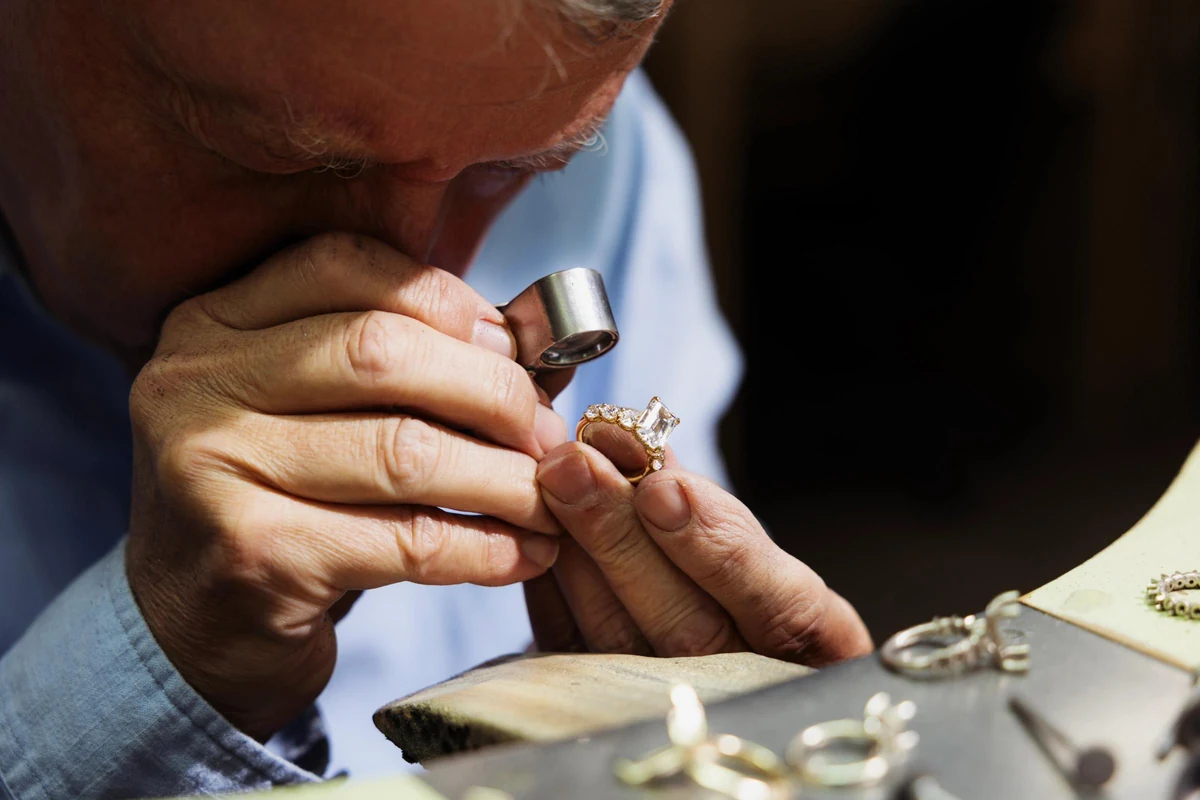 A Tacori artisan examines fine jewelry at the workbench through a jeweler’s loupe