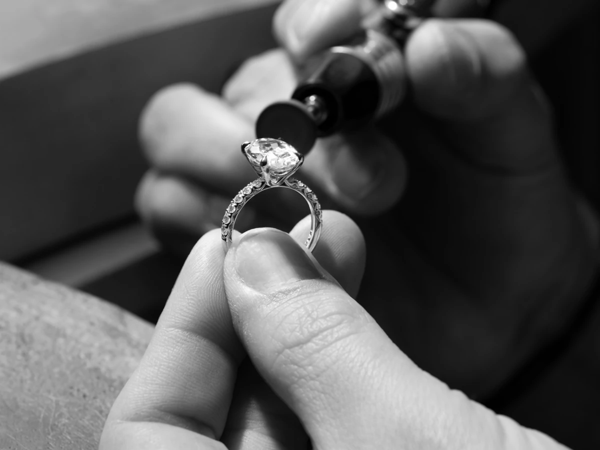 A Tacori artisan inspects the details of a ring through a jeweler’s loupe.
